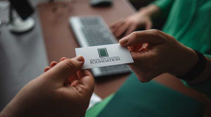two hands exchanging a United Pentecostal Foundation business card